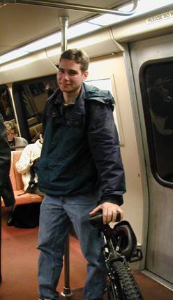 Picture shows a man with a bicycle riding in a subway car.