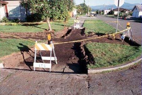 This picture shows a sidewalk that has been closed due to construction. Barriers and plastic tape have been placed to discourage pedestrian travel through the construction zone, but no apparent alternate route for pedestrians has been provided.