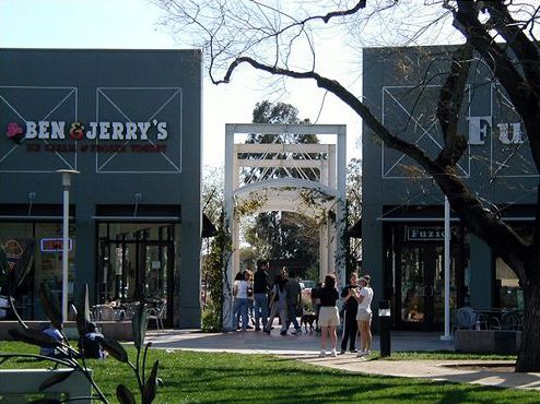 The picture shows a new-looking shopping development with a gateway structure between buildings. By creating a landmark the connection to the parking area is easier to find. 