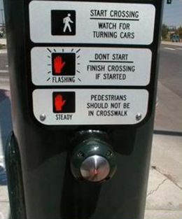 The picture on the right shows a close–up view of a pushbutton and supplemental plaque that has three panels stacked horizontally. The top one has a box with a person walking, and to the side, the instructions, "START CROSSING. WATCH FOR TURNING CARS" The middle panel of the plaque has a box with a hand in it, the word "FLASHING" over it, and the instructions, "DON’T START. FINISH CROSSING IF STARTED" The bottom panel has a box with a hand in it, the word "STEADY" over it, and the instructions, "PEDESTRIANS SHOULD NOT BE IN CROSSWALK".