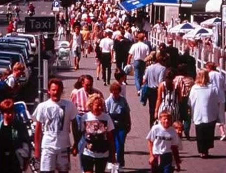 This slide shows a picture of a busy sidewalk that has many people walking.