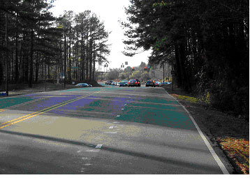 Figure 16. Photograph.  Street view of bicycle example 1. This is one of three photographs of the same intersection. This picture, from the street level, shows the signalized intersection of two roads. The main approach road is a two-lane road with separate left- and right-turn lanes approaching the intersection. The crossing street is a four-lane road with a separate left-turn lane.