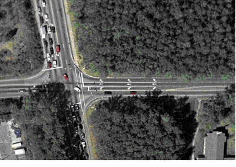 Figure 18. Photograph. Overhead photo of bicycle example 1 (image courtesy of the United States Geological Survey). This picture is an aerial view of the same intersection shown in Figures 16 and 17. An arrow pointer marks the approach to the intersection from the east.