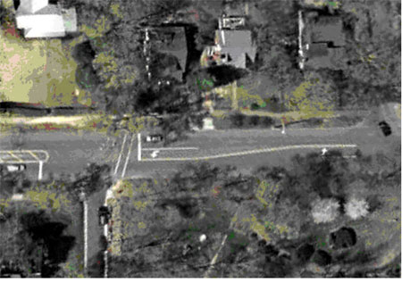 Figure 25. Photograph. Overhead view of bicycle example 2 (image courtesy of the United States Geological Survey). This picture is an aerial view of the same intersection as in Figures 23 and 24. An arrow pointer marks the approach to the intersection from the east.