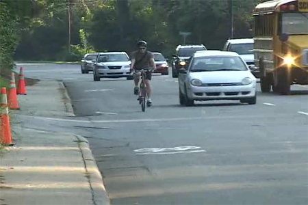 Photo. Motor vehicle passing a bicycle after sharrow placement with traffic in the adjacent lane. Click here for more information.