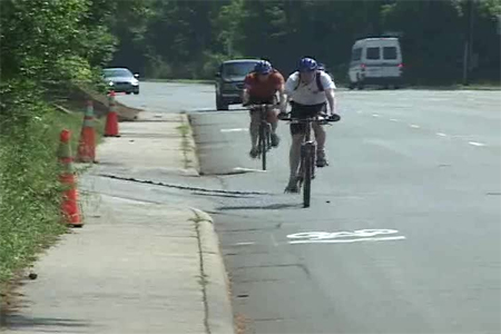 Photo. Bicyclists riding over the sharrow in the outbound (downhill) direction. Click here for more information.