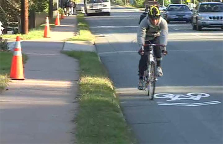 Photo. Bicyclist riding next to the sharrow in the inbound (uphill) direction. Click here for more information.