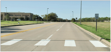 Figure 2. Photo. Example of continental markings installed for this study. This photo shows an example of the continental markings installed at one of the study sites. Each strip is a white longitudinal marking that is 24 inches wide and 10 ft long. The strips are located on the edge and in the middle of the travel lanes.