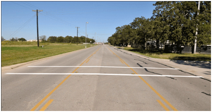 Figure 3. Photo. Example of transverse markings installed for this study. This photo shows an example of the transverse markings installed at one of the study sites. The markings consist of two parallel, white transverse lines that are each 12 inches wide. The distance between the two strips is 8 ft.