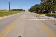 This photo shows an example of the transverse markings installed at the study site on F&B Road. The markings consist of two parallel white transverse lines that are each 12 inches wide. There is 8 ft between the two strips.