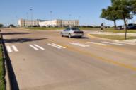 This photo shows the bar pairs markings installed at the study site on Agronomy Road. Each bar pair consists of two 8-inch strips of parallel white longitudinal markings separated by 8-inch spacing. The strips are 10 ft long. The bar pairs are located on the edge and in the middle of the travel lanes.