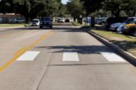 This photo shows the continental markings installed at the study site on Agronomy Road. Each strip is a white longitudinal marking that is 24 inches wide and 10 ft long. The strips are located on the edge and in the middle of the travel lanes.