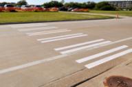 This photo shows the bar pairs markings installed at the study site on Penberthy Road. Each bar pair consists of two 8-inch strips of parallel white longitudinal markings separated by 8-inch spacing. The strips are 10 ft long. The bar pairs are located on the edge and in the middle of the travel lanes.