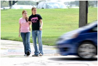 In this example of a conflict, a motor vehicle that appears to be moving quickly comes close to striking two pedestrians as they attempt to cross the street.