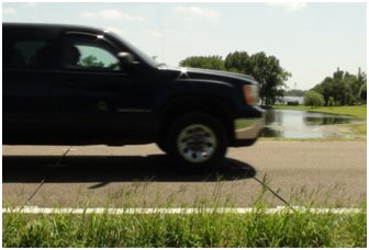 A motor vehicle passes over two sets of road tubes, the data from which will be used to determine the vehicle's speed and whether the driver is using gradual or panic braking.