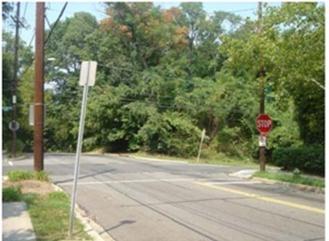 Figure 3. Photo. Example of a stop controlled (all-way) intersection. This photo shows an example of a stop-controlled (all-way intersection). The intersection is a four-way intersection with stop signs at all sides. There are sidewalks and trees on all sides of the road.