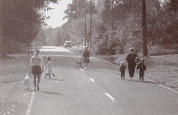 roadway without a sidewalk with pedestrians walking along it