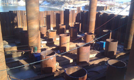 Eighteen open-end pipe piles are shown. The piles are 42 inches in diameter, and are located on a pier and a body of water is visible in the background.