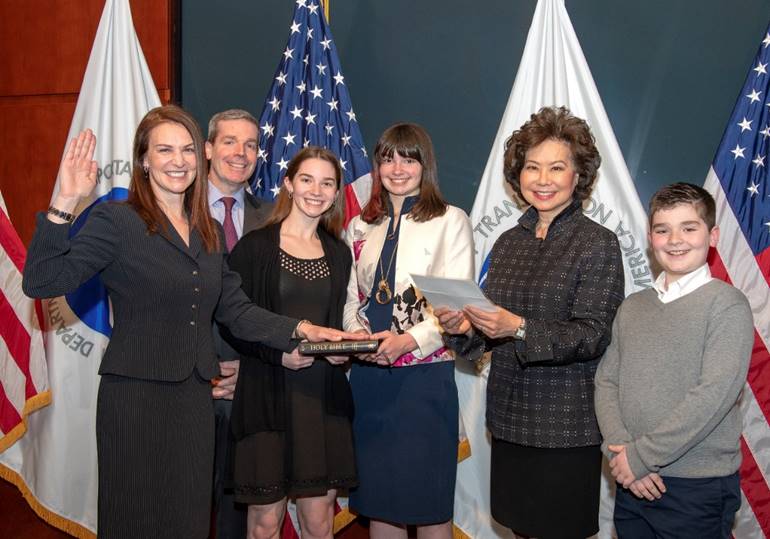 U.S. Secretary of Transportation Elaine L. Chao swears in Nicole R. Nason as Nason's family stands with her.