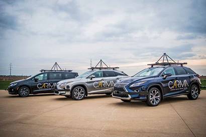 Three sport utility vehicles are parked on a lot. Each vehicle has instrumentation affixed to the roof and affixed on the front end of the vehicle.