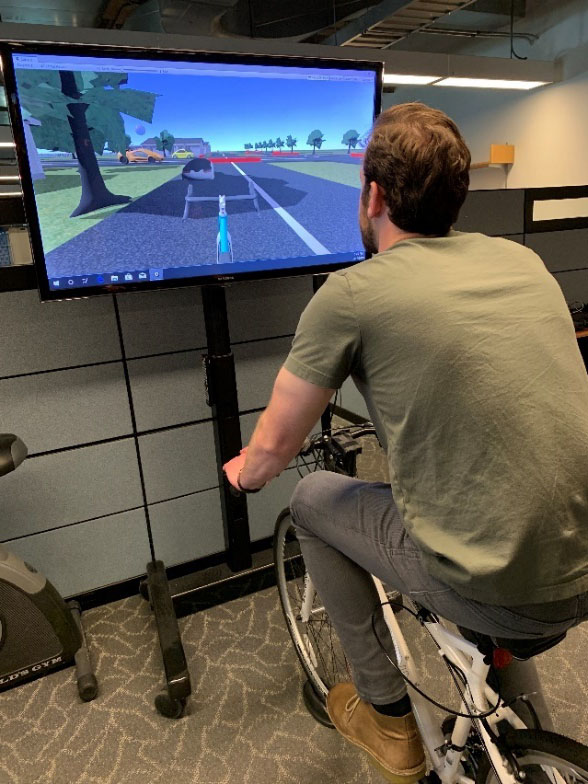 Person on a bicycle connected with a virtual display showing a roadway and vehicles.