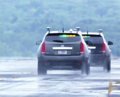 The green and yellow lights on the test vehicles indicate communication and connectivity between the cars.