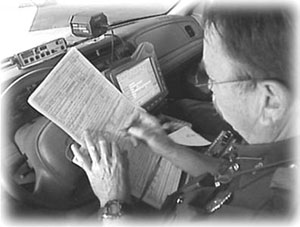 Police officer filling out a crash report in his vehicle