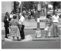 Photo of pedestrians standing on a depressed median, four-lane separator waiting to cross