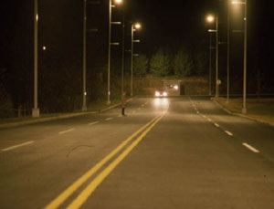 high level of overhead lighting on roadway, pedestrian visible