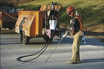 Caption: A worker seals a transverse joint along a roadway. One potential use of FHWA's new software system is to help project planners determine the need to seal pavement joints.