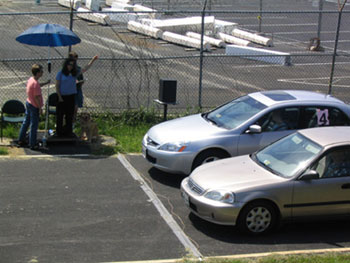 a visually impaired participant is shown raising her hand to indicate that two cars have yielded and that is safe to cross