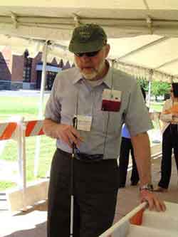 Kenneth L. Stewart from the Council of Citizens with Low Vision International manually examines a barrier.