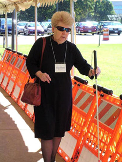 Patricia M. Beattie from the National Industries for the Blind taps her cane against the bottom of a barrier to evaluate its effectiveness.