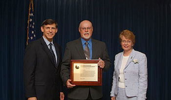William Ruediger of Montana, the first ecology program leader for highways for the United States Department of Agriculture Forest Service, won the 2005 FHWA Environmental Leadership Award. Ruediger (center) is shown above accepting his award from FHWA Deputy Administrator J. Richard Capka and Associate Administrator for Planning, Environment and Realty Cynthia J. Burbank.