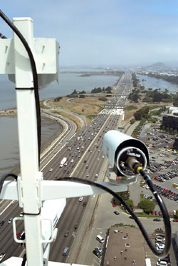 A digital camera mounted on top of a building that overlooks a highway is recording vehicle trajectory datasets for FHWA's NGSIM program.