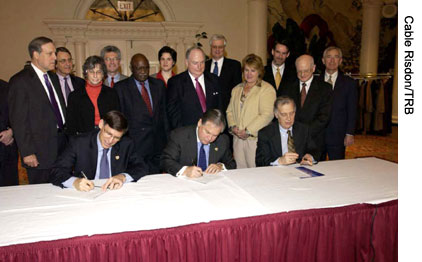 HWA Acting Administrator J. Richard Capka, AASHTO Executive Director John Horsley, and NAS President Ralph J. Cicerone (seated left to right) sign the SHRP II MOU on January 25, 2006, with attendees of the TRB Executive Committee meeting looking on.