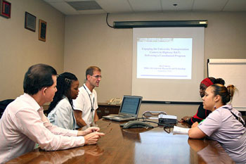 These FHWA staff members sitting around a computer in a meeting room are participating in a Web conference on the UTC program.