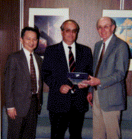 Dr. Juan Pablo Covarrubias, of the Chilean Cement and Concrete Institute (center), delivers FHWA’s copies of Pavement Evaluator to Henry Rentz and Paul Teng from the Office of Engineering.