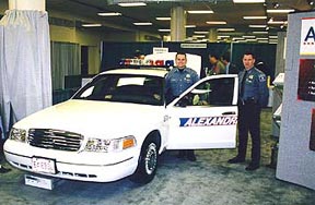 Two police officers stand next to an Alexandria, VA police car