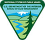 BLM Logo featuring an evergreen tree and river in the foreground and a snow-capped mountain in the background. The logo is triangular in shape. It says "U.S. Department of the Interior Bureau of Land Management" at the top.