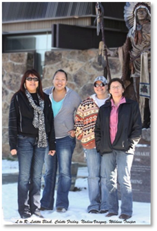 Photo of four people in winter wear in fronte of a stone wall. 