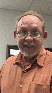 Photo of Billy Gordon wearing an orange shirt and glasses.