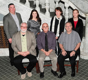 This is a group photo of seven people who helped develop Kansas DOT's online right of training for local public agencies. The group is standing beside a granite staircase.
