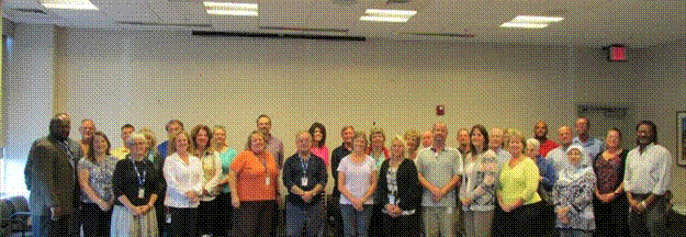 This is a group photo of approximately 34 people representing DelDOT's right of way section. The group is standing inside in a large conference room.