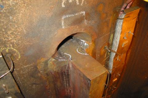 Figure 8 Pile 5 plate D at upper end showing MP indication at gouge which was removed by grinding. The weld ends have not been finished after runoff tab removal.