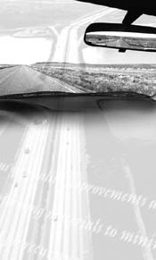 Black and white photo of an open road as viewed from behind a car dashboard