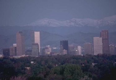 Photo of slightly hazy Denver, CO skyline taken looking west with the Rocky Mountains in the background.