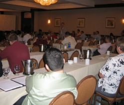 Photo of Environmental Conference attendees sitting at conference tables while listening intently to a presentation.