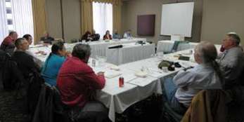 Caption: Photo of Tribal consultation meeting, showing participants in a meeting room sitting at conference tables.  