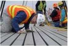 Photo of rescue workers examining a series of boards laid across an unpictured surface.